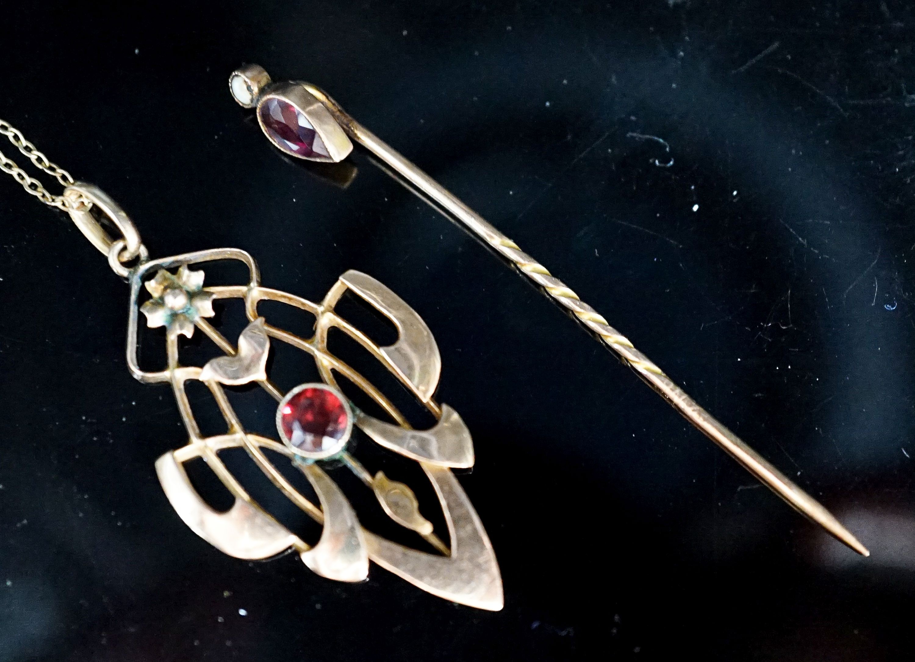 An Art Nouveau yellow metal and garnet set pendant,39mm, on a 9ct chain and a garnet and split pearl set stick pin, gross weight 5.8 grams.